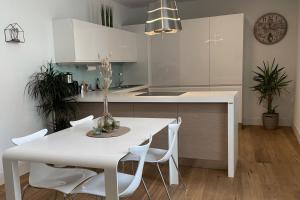 biała kuchnia z białym stołem i krzesłami w obiekcie Apartments Griesser w mieście Bressanone