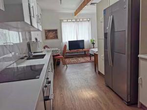a kitchen with a refrigerator and a living room at Sunshine Gardens Bourke Resort in Bourke