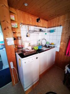 La cuisine est équipée d'un réfrigérateur blanc et d'un évier. dans l'établissement Ferienhaus mit riesen Garten, drei Terrassen, toller Aussicht am Waldrand, auch als Monteur-Wohnung, à Hemer