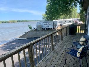 una terraza con sillas y rvs en el agua en Mississippi River Cabin, en Bellevue