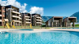 a resort with a swimming pool in front of a building at Departamento Costa Pucón 403 in Pucón