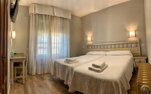 1 dormitorio con 1 cama grande y toallas. en Hostal Restaurante Méndez en Villafranca del Bierzo