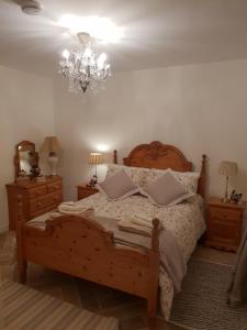 a bedroom with a wooden bed and a chandelier at Kiltoy Cottage, Cosy 2 bedroomed Gate Lodge Cottage in Letterkenny