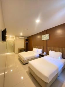 a hotel room with two beds and a bathroom at Hotel Jelai @ Raub, Pahang in Raub
