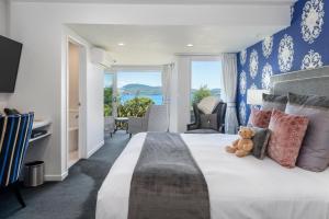 un dormitorio con una cama grande con un osito de peluche sentado en él en Black Swan Lakeside Boutique Hotel en Rotorua