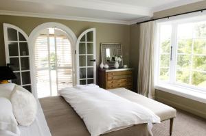 a bedroom with a bed and a mirror and windows at Ngamihi Lodge in Rotorua