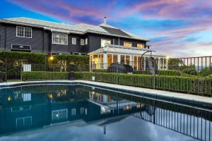 a house with a swimming pool in front of a fence at Black Swan Lakeside Boutique Hotel in Rotorua