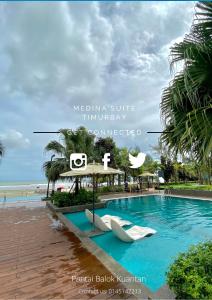 a swimming pool at a resort with a beach at Medina Suite Timurbay in Kuantan