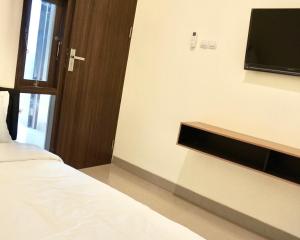 a bedroom with a bed and a flat screen tv at RedDoorz at Arkana Seturan Pakuwon Mall in Yogyakarta