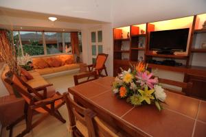 a living room with a table with flowers on it at La Ceiba del Mar in Zihuatanejo