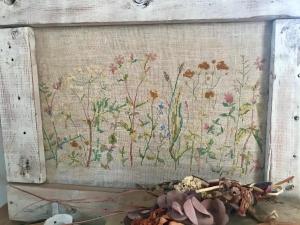 a tapestry hanging on a wall with flowers at Travelers House おーさんてぃん青空舎 in Taketomi