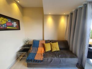 uma sala de estar com um sofá de couro com almofadas amarelas em Winterville Resort Flat 910 Gravatá-Pe em Gravatá