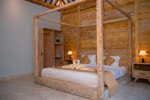 ein Schlafzimmer mit einem Bett mit einem Holzrahmen in der Unterkunft Alwi Villa Gili Trawangan in Gili Trawangan