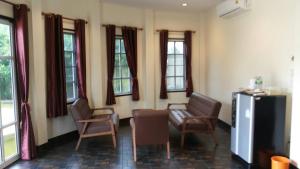 a living room with chairs and a couch and windows at Wangthong Beach Resort in Laem Sing