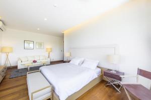 a bedroom with a large white bed and a couch at The Gallery Khao Yai Hotel and Residence - SHA Plus in Khao Yai