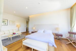a bedroom with a large white bed and a couch at The Gallery Khao Yai Hotel and Residence - SHA Plus in Khao Yai
