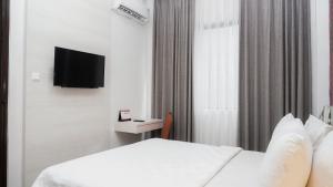 a hotel room with a bed and a tv at Alam Hotel by Cordela in Medan