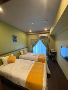 宮古島にあるHOTEL Fit in Miyakojimaのベッド2台とテレビが備わるホテルルームです。
