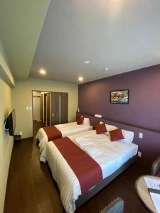 una camera d'albergo con due letti e una parete viola di HOTEL Fit in Miyakojima a Miyakojima