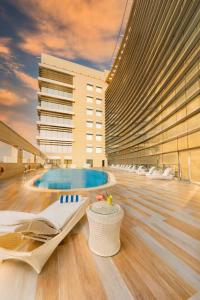 a large building with a pool and lounge chairs at dusitD2 Salwa Doha in Doha