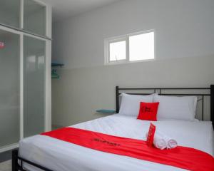 ein Bett mit zwei roten Kissen und einer roten Decke in der Unterkunft RedDoorz near Tamansari Shopping Center Salatiga in Salatiga