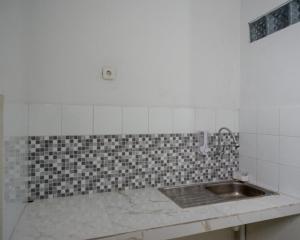 eine Küche mit einem Waschbecken und einer gefliesten Wand in der Unterkunft RedDoorz near Tamansari Shopping Center Salatiga in Salatiga