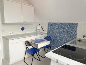 a kitchen with white cabinets and blue chairs in it at Fewo Haus Piepenbreier in Bad Sassendorf