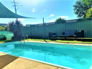 a swimming pool in a yard with a fence at Bradman Motor Inn in Cootamundra