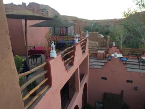 a pink building with a balcony with an umbrella at Kasbah du Peintre in Aït Ben Haddou