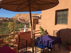 a patio with a table and chairs under an umbrella at Kasbah du Peintre in Aït Ben Haddou
