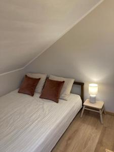 een bed met 2 kussens en een tafel met een lamp bij Brezno Apartament in Gdańsk
