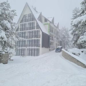 ein schneebedecktes Gebäude mit einem davor geparkt in der Unterkunft Studio Djurdja in Divčibare