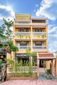 a large yellow building with a balcony at Virgo Villa Quê Hội An in Hoi An