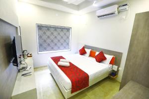 Schlafzimmer mit einem Bett mit roten Kissen und einem TV in der Unterkunft Classio Residency in Puducherry