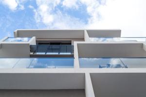 a view of the facade of a white building with glass windows at δ193 in Volos