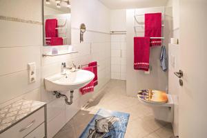 a bathroom with a sink and a toilet and red towels at Haus Ruther - Apartment in Bad Saulgau