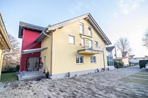 a yellow and red house with a brick driveway at Haus Ruther - Apartment in Bad Saulgau