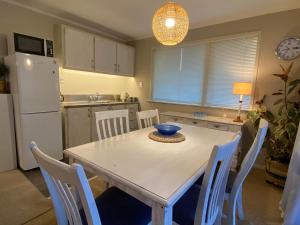 cocina con mesa y sillas blancas y nevera blanca en Feel at Home en Tauranga