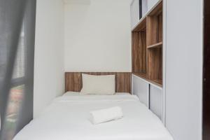 a small bedroom with a bed and wooden cabinets at Premium Relaxing 2BR at Casa de Parco Apartment By Travelio in Samporo +17 photos