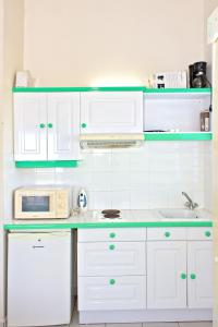 a kitchen with white cabinets and a sink and a microwave at Studio avec piscine partagee jardin et wifi a Sainte Anne a 3 km de la plage in Sainte-Anne