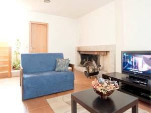 ein Wohnzimmer mit einer blauen Couch und einem Fernseher in der Unterkunft Comfortable Countryside House in Eira-Vedra with Shared Pool in Vieira do Minho
