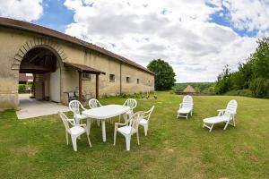 a group of white chairs and a table in the grass at Maison accueillante près de Monthenault, parfaite pour groupes in Monthenault