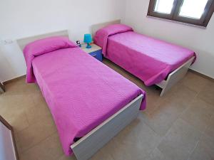 サンタンナ・アッレージにある2 bedrooms house with enclosed garden and wifi at Sant'Anna Arresi 3 km away from the beachのピンクのシーツが備わる客室内のベッド2台