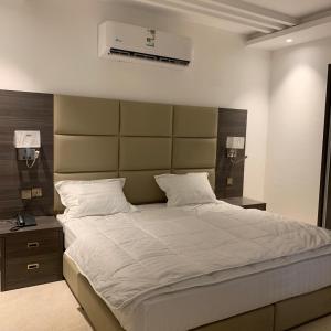 um quarto com uma cama grande e uma grande cabeceira. em الأمــــان للشـقـق المـخـدومـة em Medina
