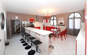 une cuisine avec des placards rouges, une table et des chaises dans l'établissement Demeure de 6 chambres avec piscine interieure jacuzzi et jardin clos a Vernou sur Brenne, à Vernou-sur-Brenne