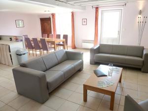 a living room with two couches and a table at Maison de charme à Saint-Vincent-la-Châtre avec piscine partagée in Saint-Vincent-la-Châtre