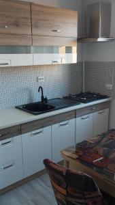 a kitchen with white cabinets and a sink and a table at Studio Elisa in Caransebeş