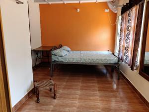 a bed in a room with a table and a bench at Hanakodu homestay in Sringeri