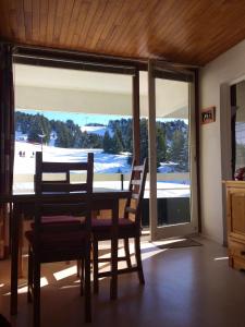 a dining room with a table and chairs and a large window at Appartement d'une chambre avec balcon amenage a Chamrousse in Chamrousse