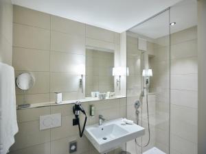 a white sink sitting under a mirror in a bathroom at Deltapark Vitalresort**** in Thun